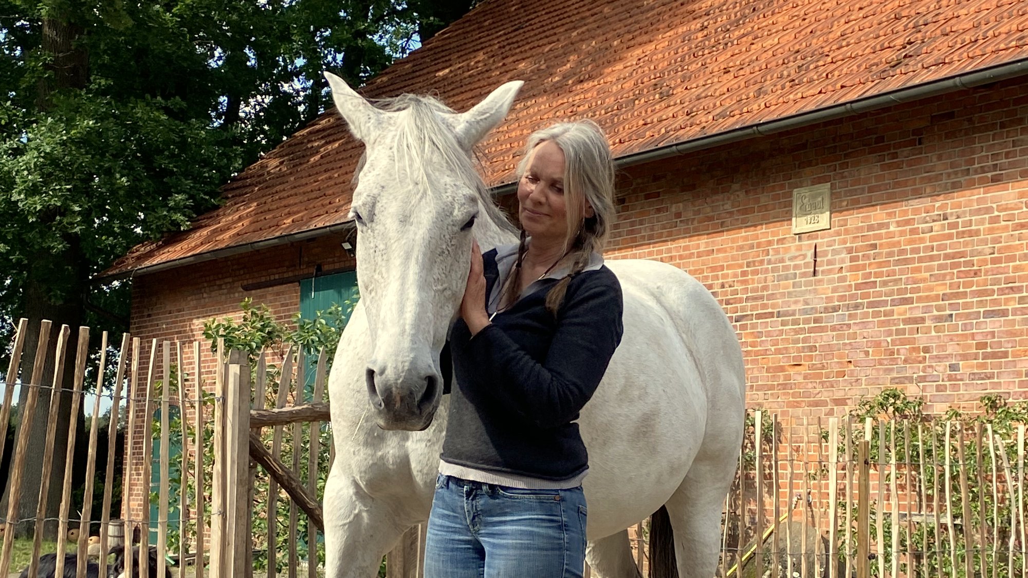 Dr. Silke Volkmann mit ihrer Schimmelstute Cleo vor der Scheune auf dem Hof